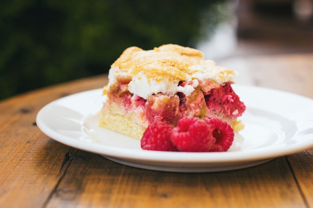 Délicieux gâteau aux framboises fait maison avec de la crème fouettée sur une assiette, parfait pour les amateurs de desserts.