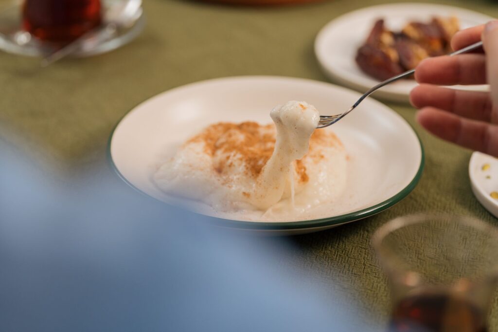 Gros plan d'une fourchette soulevant un dessert traditionnel turc avec en toile de fond un service de table, capturant l'essence de la cuisine turque.