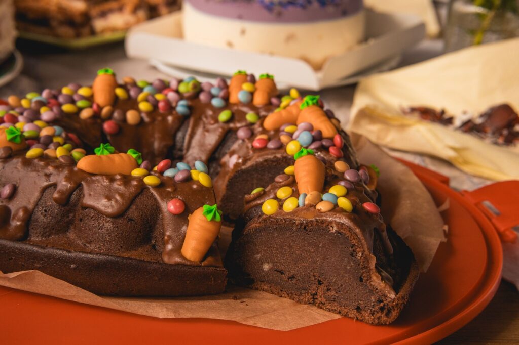 Un riche gâteau au chocolat garni de bonbons colorés et de décorations en carotte, parfait pour les amateurs de desserts.
