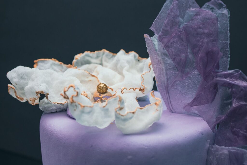 Un gâteau délicat orné de fleurs comestibles et de cristaux, avec un design élaboré.