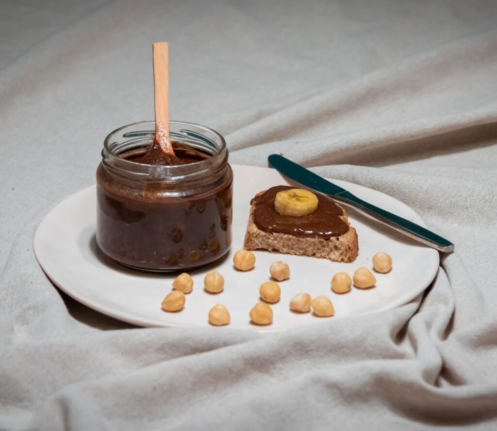 Pâte à tartiner au chocolat et noisettes avec banane sur une tranche de pain, parfait pour le petit-déjeuner.