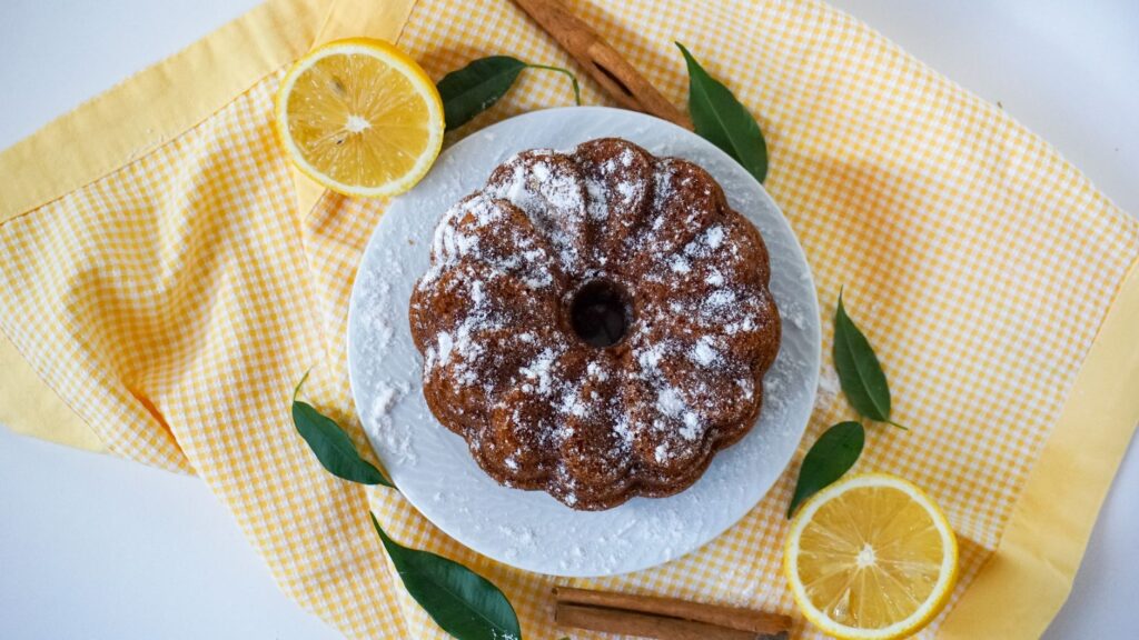 Délicieux gâteau Bundt au citron fait maison saupoudré de sucre glace sur une assiette blanche.