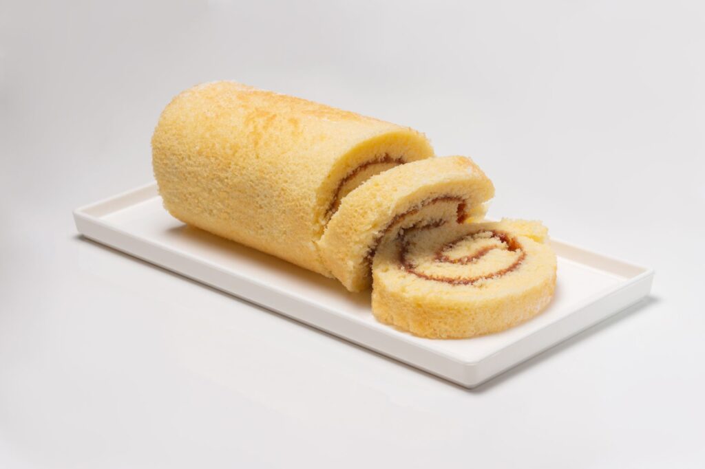 Gros plan d'un gâteau roulé vanille sucré et moelleux servi dans une assiette.