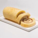 Gros plan d'un gâteau roulé vanille sucré et moelleux servi dans une assiette.