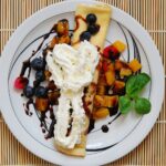 Une crêpe délicieuse garnie de fruits frais et de crème, servie dans une assiette élégante, parfaite pour un petit-déjeuner sucré.