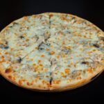 Gros plan sur une délicieuse pizza aux champignons et au fromage sur un fond sombre, parfaitement cuite.