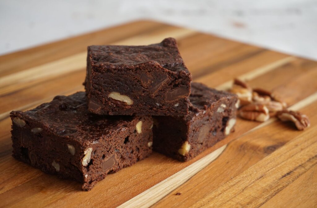 Des brownies au chocolat indulgents avec des noix sur une planche en bois rustique. Parfait pour les amateurs de desserts.