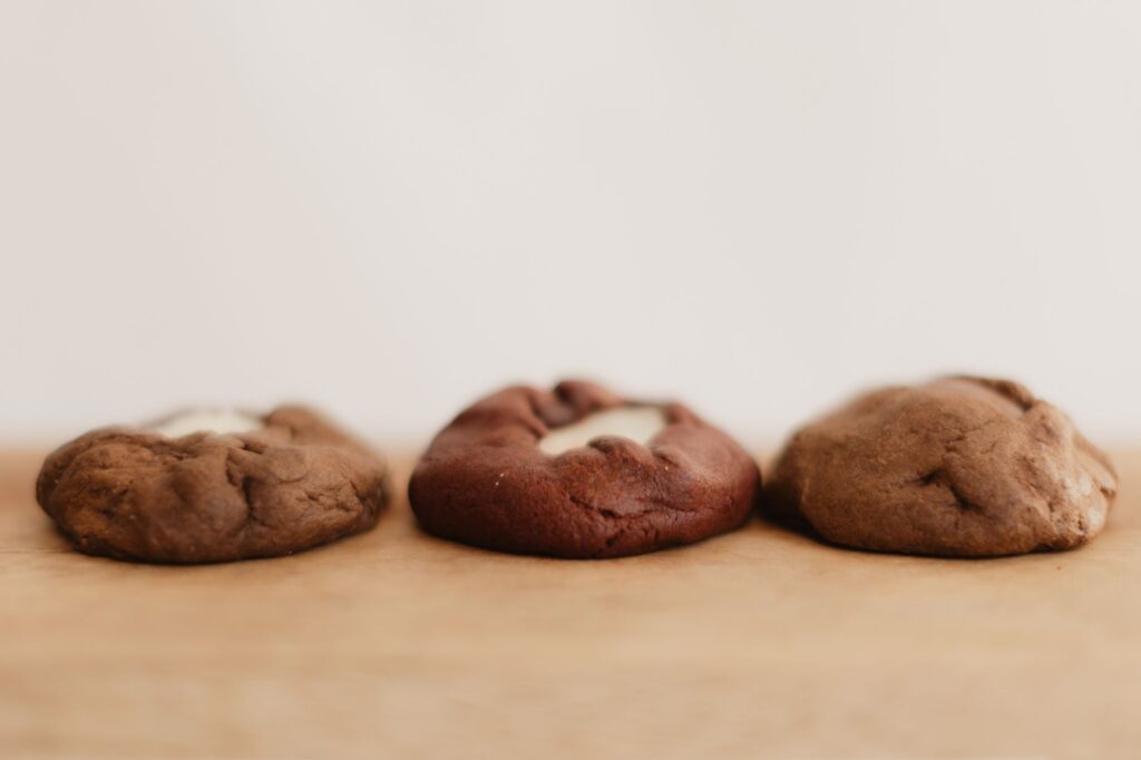 Gros plan sur trois biscuits au chocolat différents sur une surface en bois.