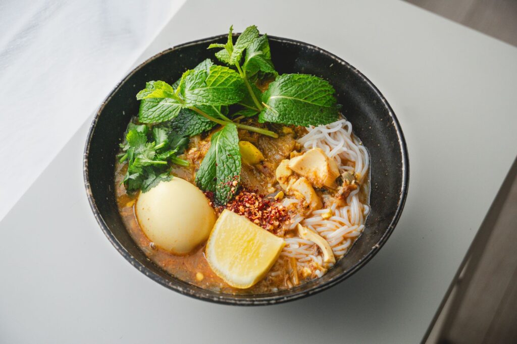Un bol de nouilles asiatiques savoureux avec des herbes fraîches, des agrumes et un bouillon savoureux.