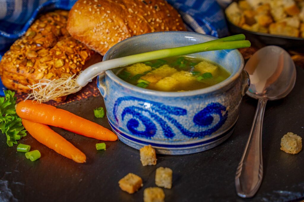 Bol chaleureux de bouillon de légumes avec croûtons et pain, parfait pour le confort d'hiver.