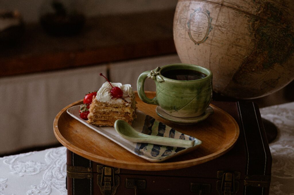 Un cadre rustique avec une tasse en céramique artisanale et une part de gâteau à côté d'un globe vintage, mettant en valeur le charme artisanal.