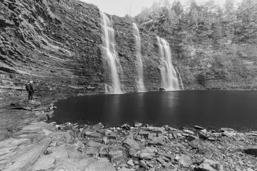 Une photographie en noir et blanc fascinante d'une cascade et de ses environs rocheux.
