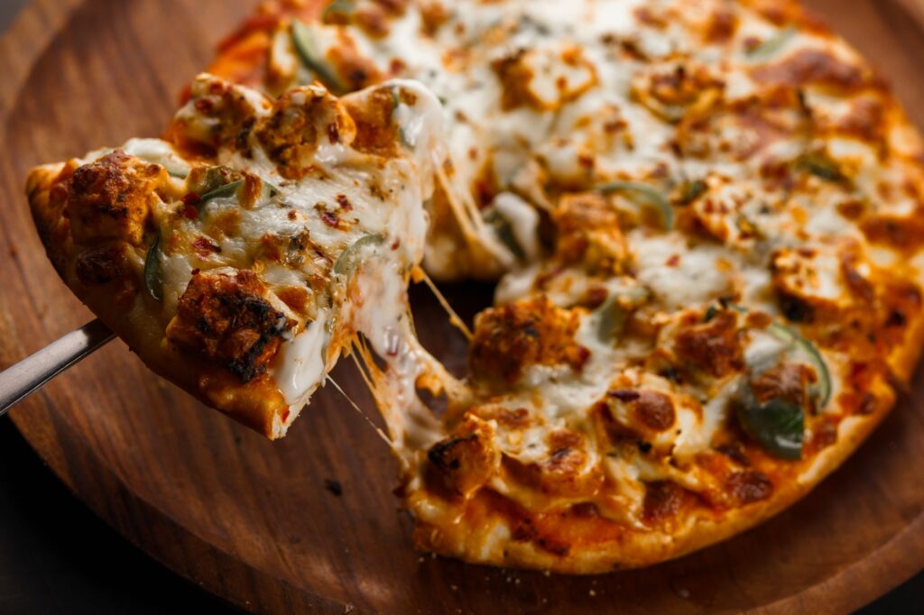 Une délicieuse tranche de pizza au pepperoni avec du fromage fondu sur une planche de bois.