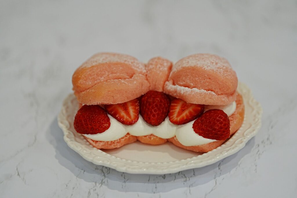 Délicieux chou à la crème fourré aux fraises avec de la crème fouettée sur une assiette décorative.