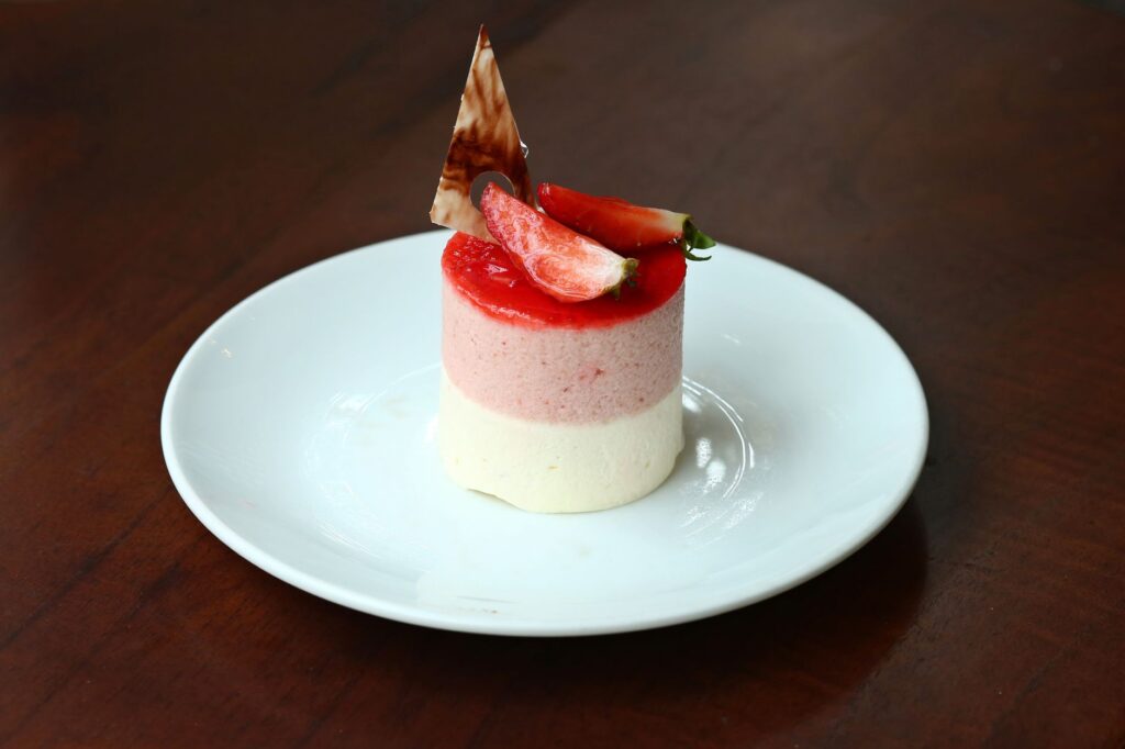 Délicieux dessert mousse aux fraises en couches avec un délicieux topping de fruits frais, servi élégamment sur une assiette blanche.