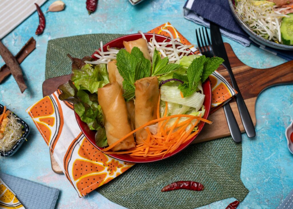 Rouleaux de printemps végétaliens colorés et salade fraîche sur une table colorée.