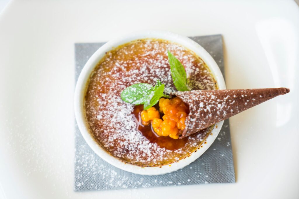 Délicieuse crème brûlée garnie de baies et d'un cône en chocolat, décorée de menthe.