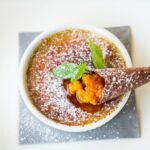 Délicieuse crème brûlée garnie de baies et d'un cône en chocolat, décorée de menthe.
