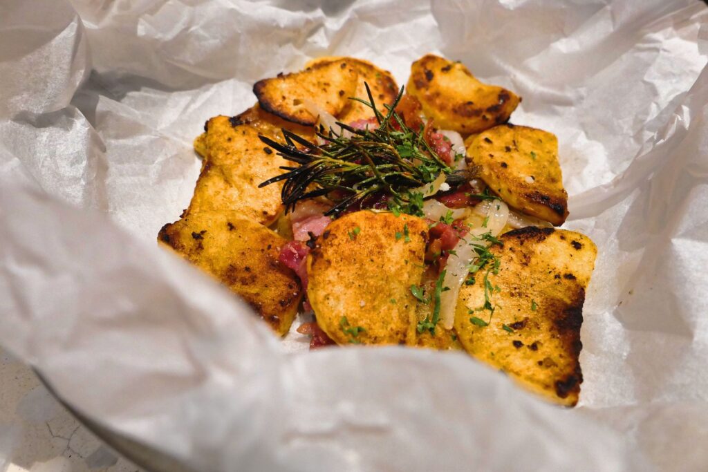 Délicieuses tranches de pommes de terre rôties de style rustique avec des herbes fraîches sur papier sulfurisé.