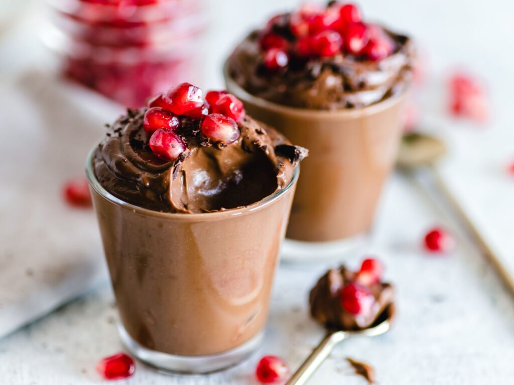 Mousse au chocolat délicieuse garnie de graines de grenade fraîches, parfaite pour les amateurs de desserts.