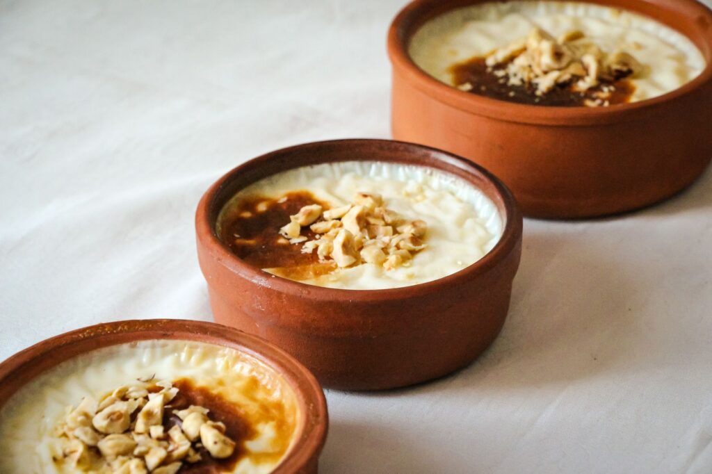 Délicieux dessert turc Güllaç servi dans des pots en argile traditionnels, garni de noix, prêt à être dégusté.