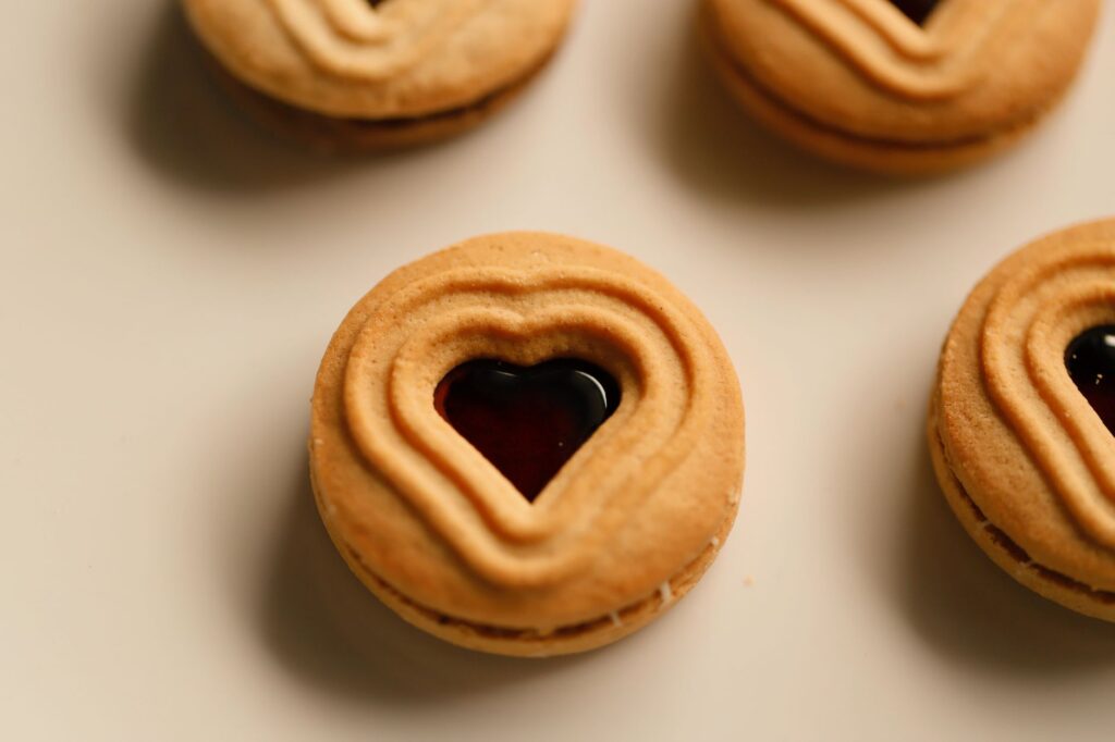 Délicieux biscuits en forme de cœur fourrés à la confiture, disposés sur une surface légère.