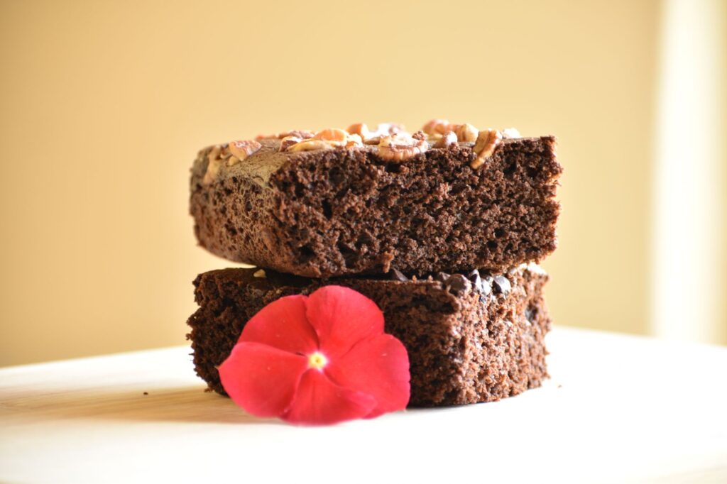 Gros plan de brownies au chocolat garnis de noix et d'une fleur rouge vif.