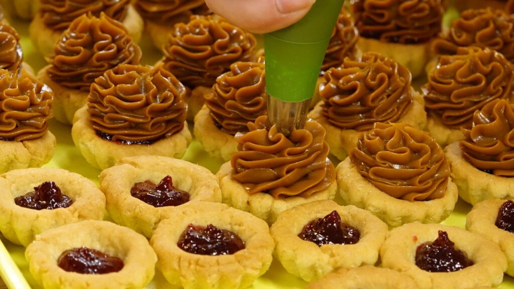 Gros plan de tartelettes fourrées de caramel et de confiture sur un plateau.