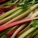 Des tiges de rhubarbe vibrantes et fraîches exposées sur un marché, mettant en valeur des couleurs et des textures naturelles.