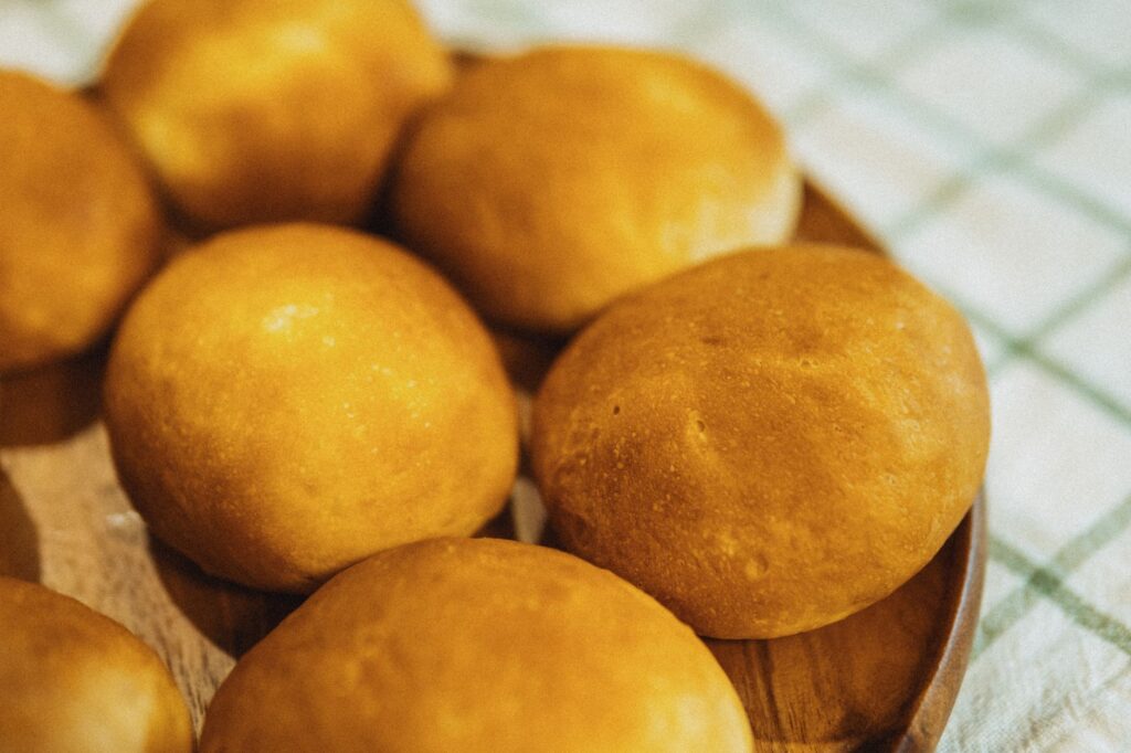 Délicieux petits pains dorés fraîchement cuits et présentés sur une assiette en bois, parfaits pour n'importe quelle cuisine.