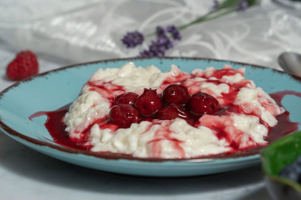 Bouillie de riz crémeuse avec sauce aux cerises, garnie sur une assiette bleu clair.