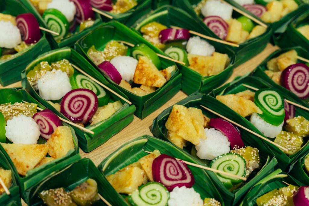 Des friandises vietnamiennes colorées présentées dans des plateaux en feuilles de banane, mettant en valeur l'art traditionnel des desserts.