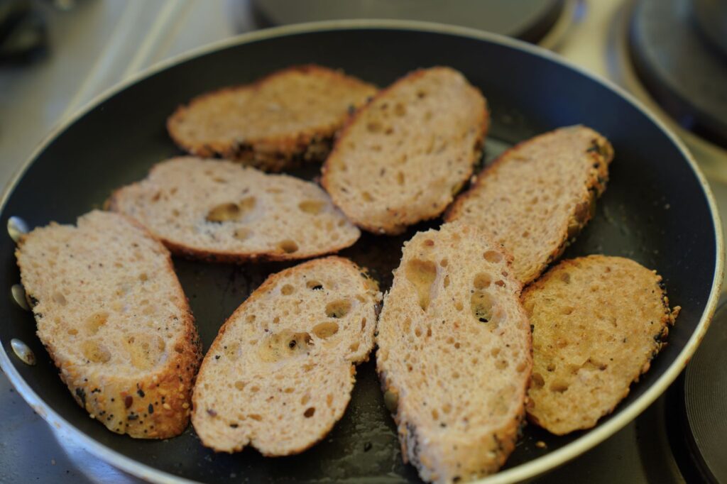 Des tranches de pain complet croustillantes qui cuisent dans une poêle antiadhésive pour un délicieux petit-déjeuner.