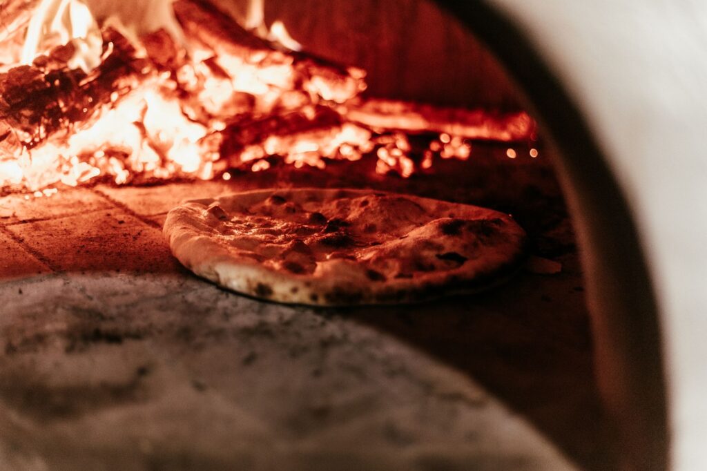 Gros plan sur une pizza cuisant dans un four traditionnel à bois.