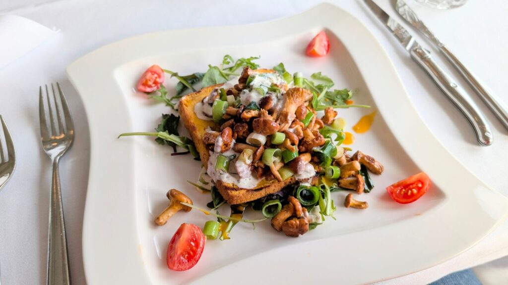Délicieux toast gourmand aux girolles et tomates servi sur une assiette blanche.