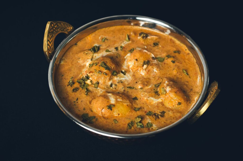 Délicieux curry Dum Aloo servi dans un bol indien traditionnel, mettant en valeur des épices riches et des herbes fraîches.