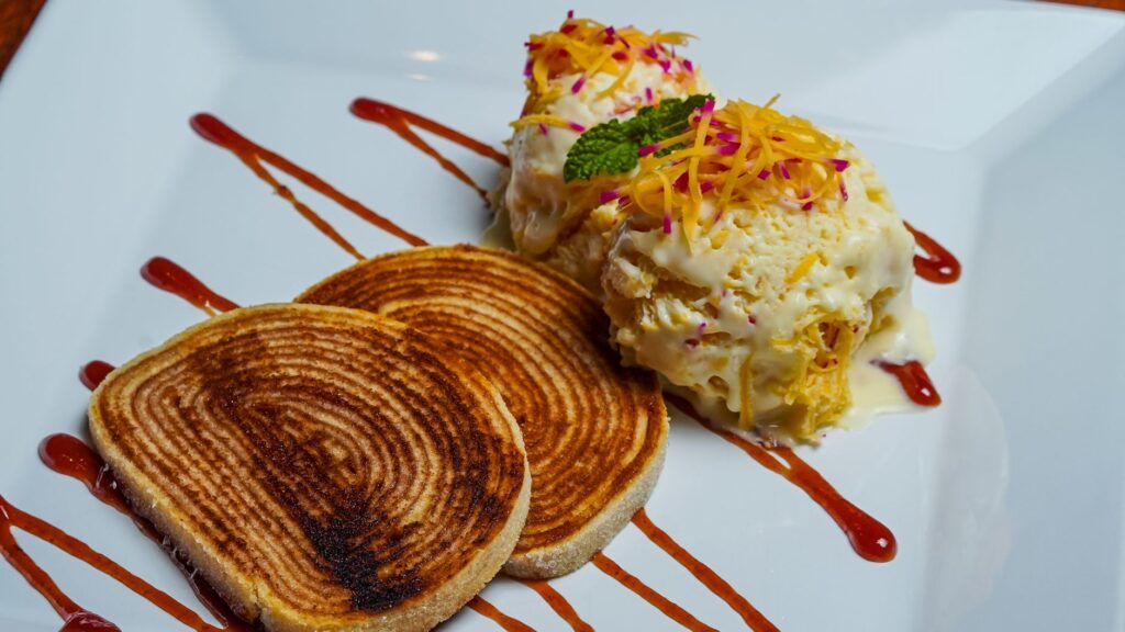Un dessert gourmet présenté délicieusement avec de la glace, du pain torsadé et une sauce décorative.