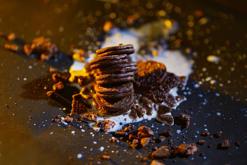 Pile de biscuits sandwich au chocolat avec du lait renversé, créant une scène de mauvaise humeur et invitante.