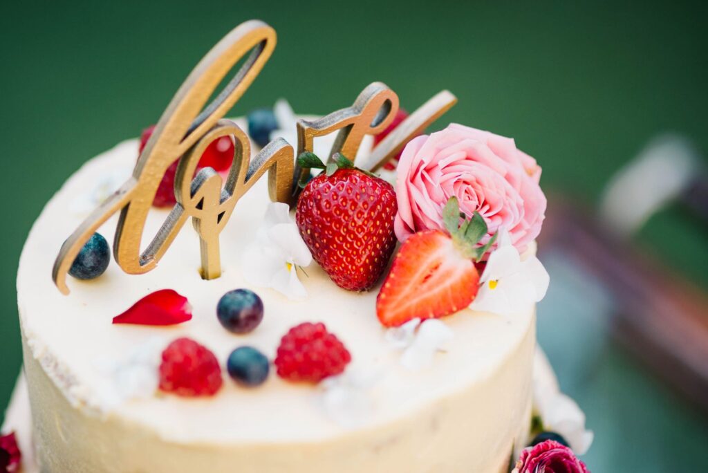 Un gâteau de mariage joliment décoré avec des baies fraîches et des roses, symbolisant l'amour.