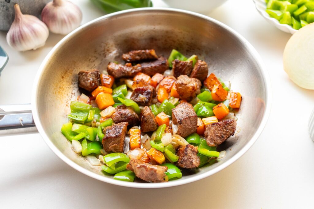 Délicieux sauté de bœuf, de poivrons et de carottes dans une poêle pour un repas dynamique.
