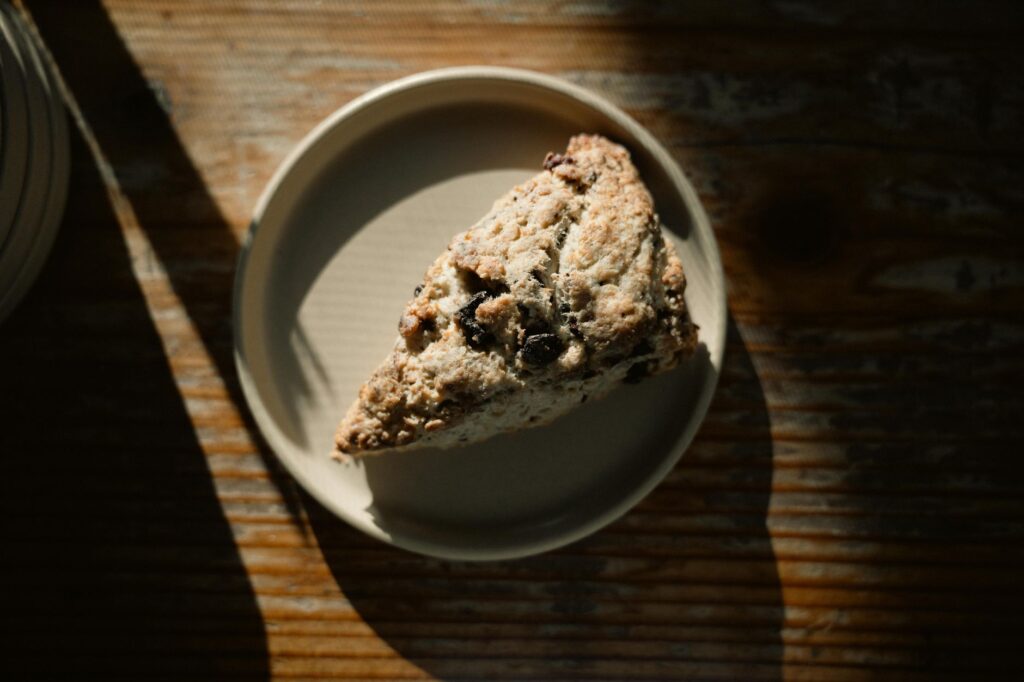 Un délicieux scone sur une assiette baignée de soleil, parfait pour un petit-déjeuner chaleureux.