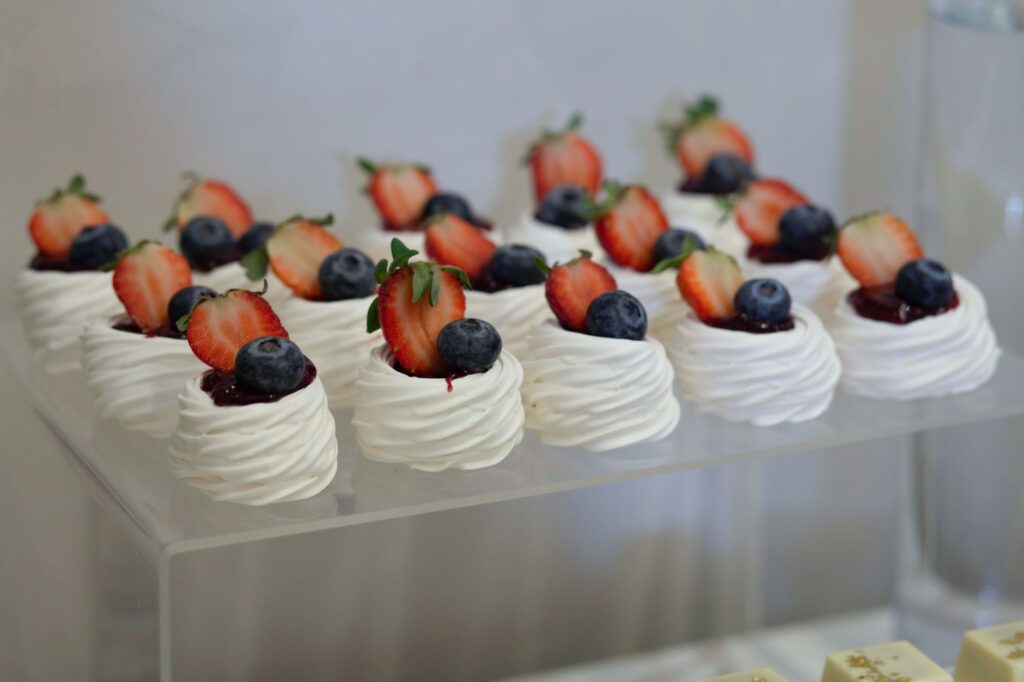 Une présentation visuellement attrayante de mini Pavlovas garnies de fraises et de myrtilles, parfaite pour les événements.