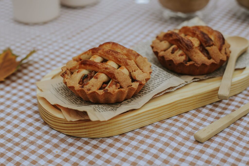 Deux mini tartelettes rustiques aux pommes servies sur une planche en bois, parfaites pour les pique-niques d'automne.