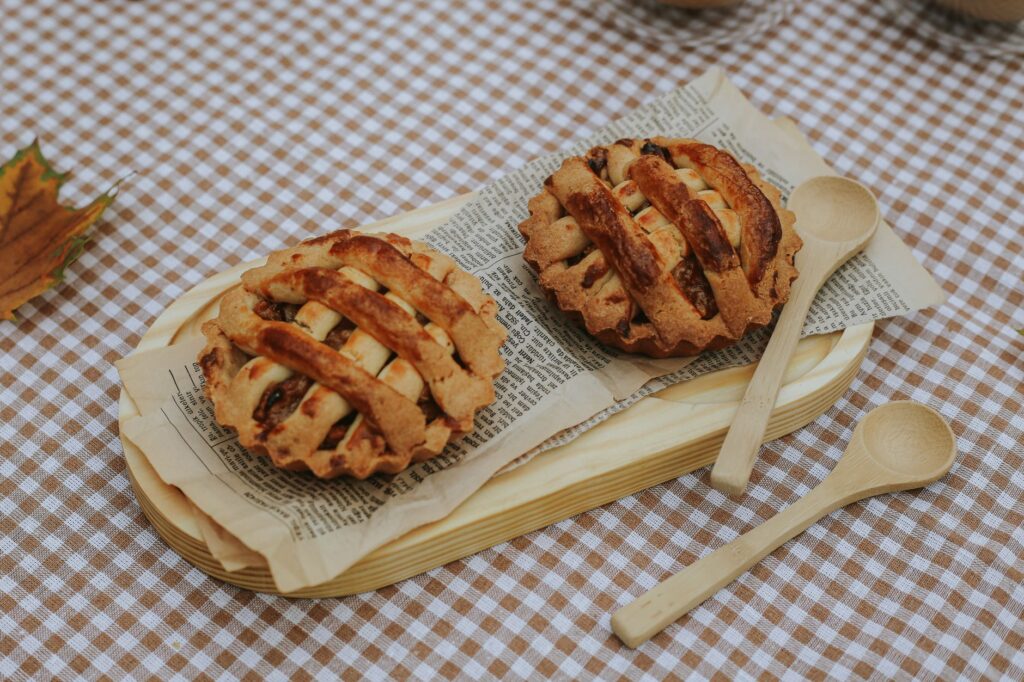 Mini tartes aux pommes rustiques sur un napperon à carreaux avec des cuillères en bois et des feuilles d'automne.