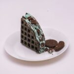 Délicieuse gaufre au chocolat et à la menthe accompagnée de biscuits, servie sur une assiette blanche, parfaite pour les amateurs de desserts.