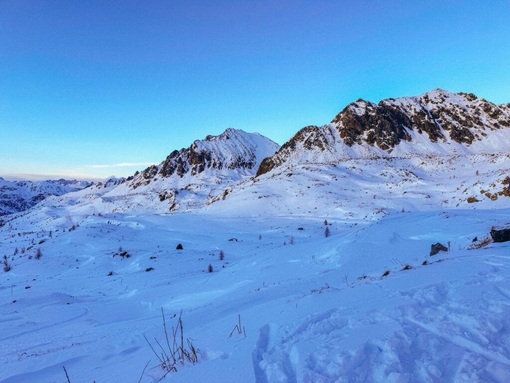 Une vue à couper le souffle des Alpes enneigées à Isola, en France, au crépuscule, offrant un panorama d'une sérénité hivernale absolue.