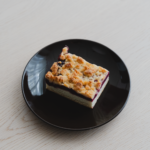 Une part alléchante de streuselkuchen fourrée aux fruits rouges, présentée sur une assiette noire, parfaite pour les amateurs de desserts.