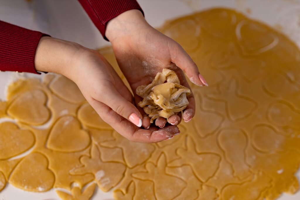 Gros plan sur des mains façonnant de la pâte en forme de cœur, parfait pour les passionnés de pâtisserie.