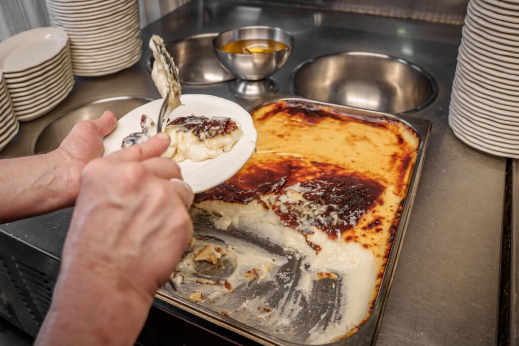 Gros plan sur des mains servant le Kazandibi, un dessert traditionnel turc, d'un plateau dans une cuisine.