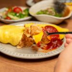 Gros plan sur un omurice japonais, un plat de riz à base d'omelette, servi avec du ketchup dans une assiette.